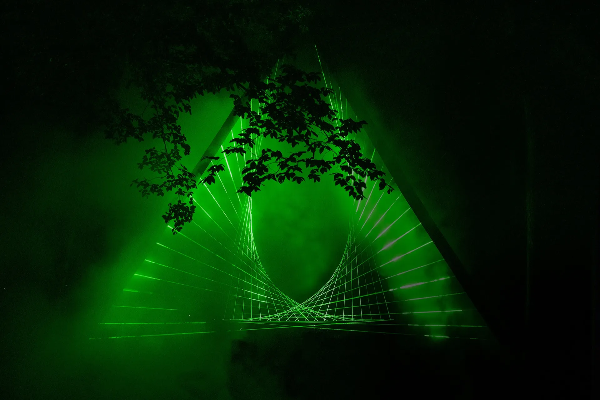 Green laser beams forming a sculpture in haze.