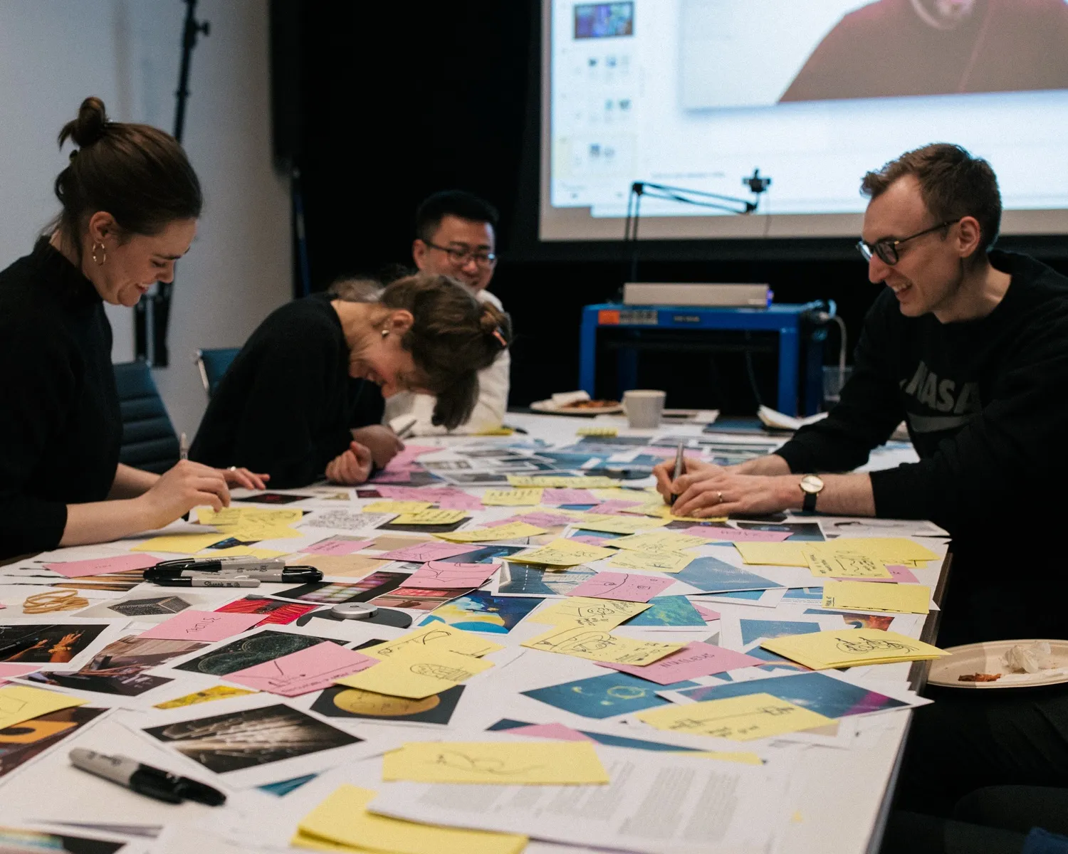 The design team and museum staff around a table covered in sticky notes.